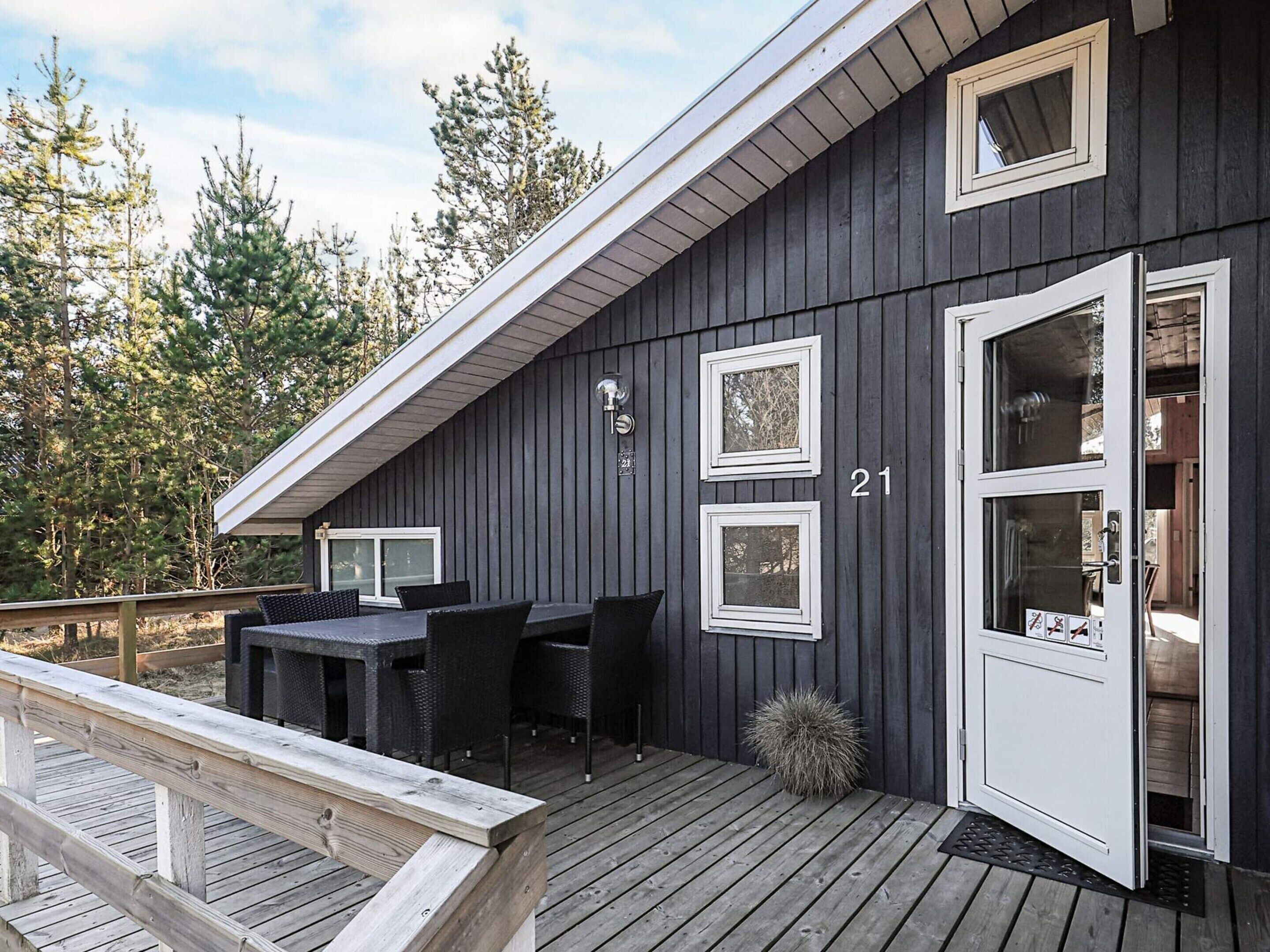 A cabin with a deck, outdoor seating, and a door with a number.