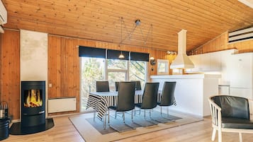 Una habitación acogedora con chimenea, una mesa de comedor, sillas y una zona de cocina.