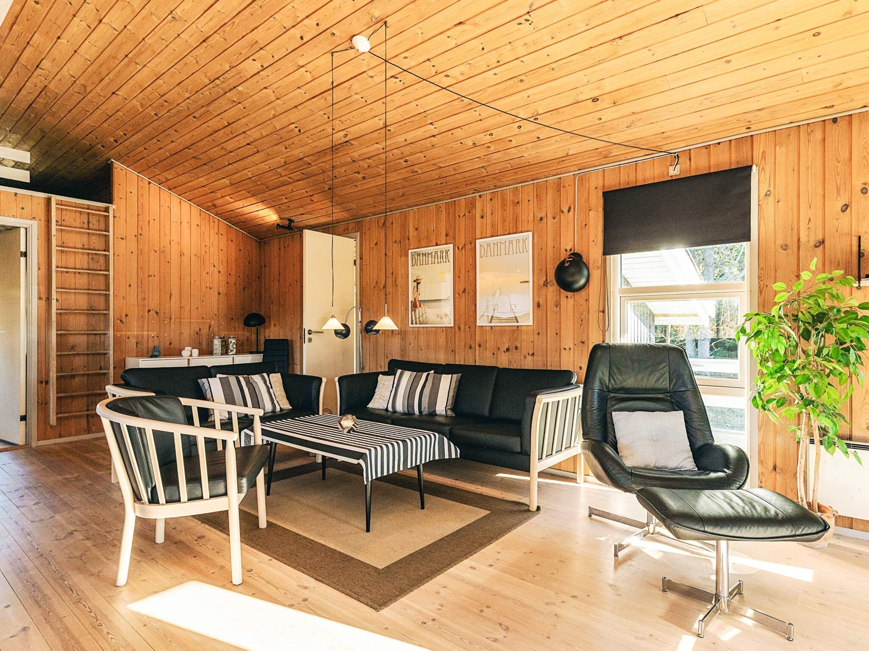 Un interior de madera con sofá, sillas, un banco y un radiador.