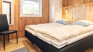 A bedroom with a bed, a chair, a window, and wooden walls. - 4 Star Holiday Home in Albaek (Aalbaek)