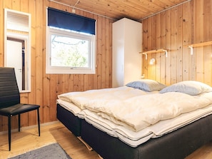 A bedroom with a bed, a chair, a window, and wooden walls. - 4 Star Holiday Home in Albaek (Aalbaek)