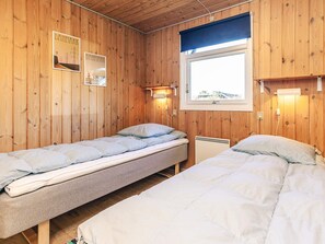 A wooden room with two single beds, a window with a view, and a wall-mounted light fixture. - 4 Star Holiday Home in Albaek (Aalbaek)