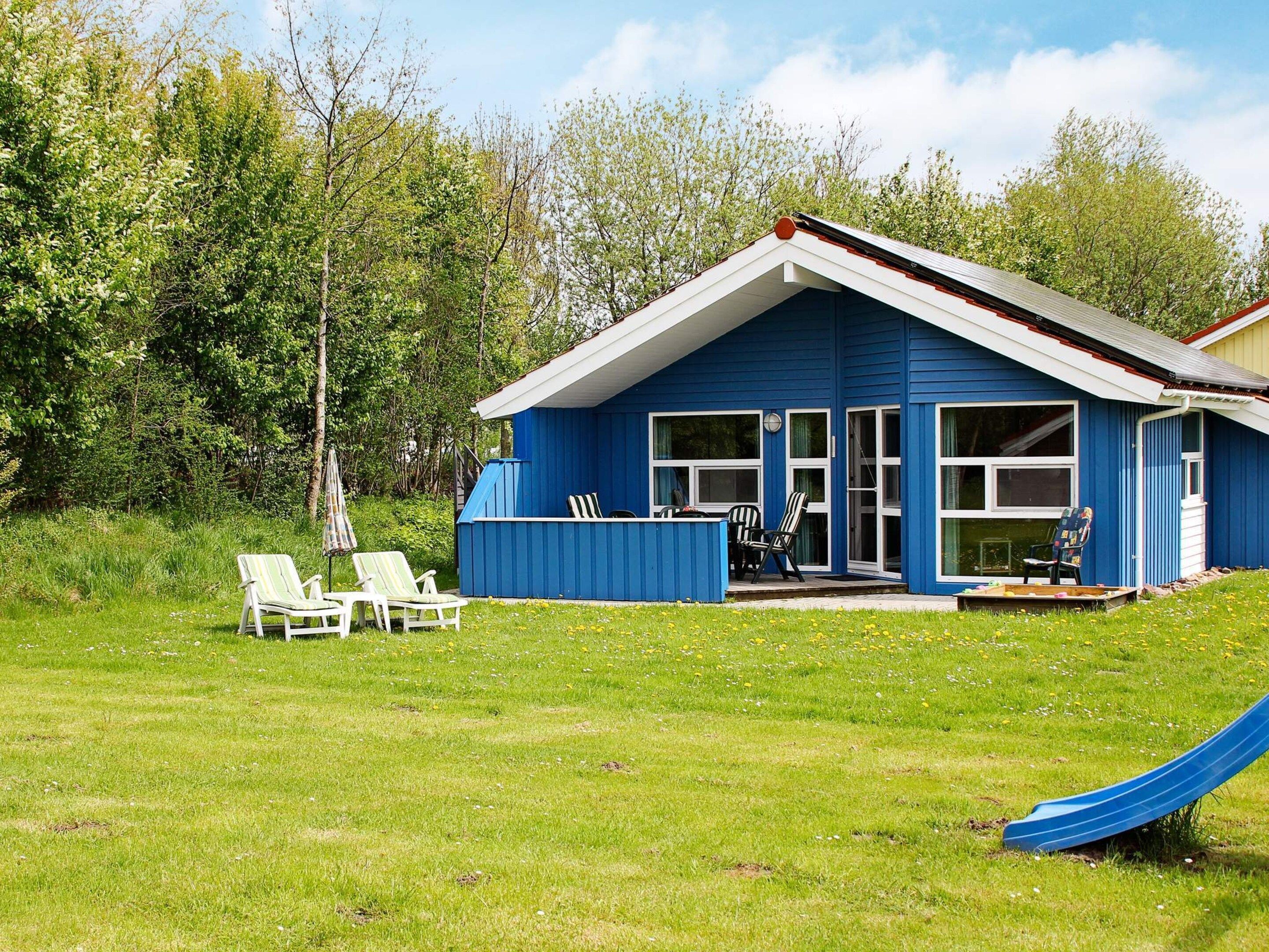 A blue house with a porch, two lawn chairs, and a slide.