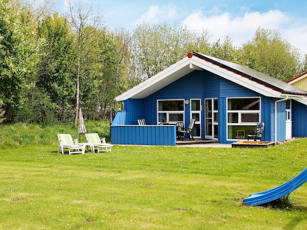 A blue house with a porch, two lawn chairs, and a slide.