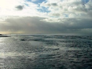 A beach with a wide expanse of wet sand and a cloudy sky. - Holiday Home in Otterndorf (Otterndorf)