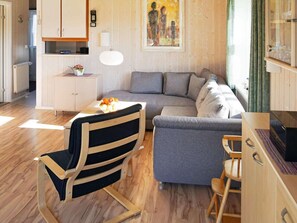 A modern living room with a grey sofa, a wooden dining table, and a black and wooden chair.