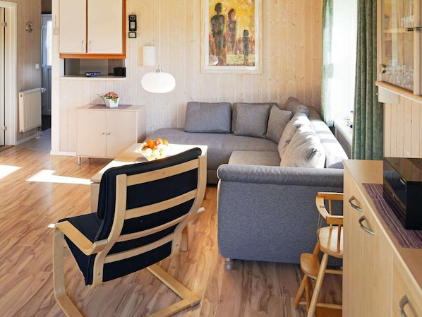 Ein modernes Wohnzimmer mit einem grauen Sofa, einem Holzesstisch und einem schwarzen Holzstuhl.