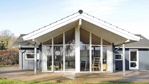 A modern house with a large covered porch, large windows, and a sloped roof. - Modern Cottage With Spa - By Traum Ferienwohnungen (Sjølund)