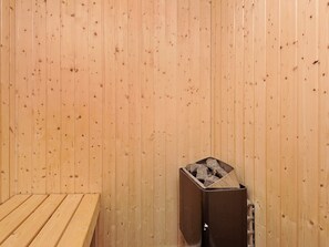 A sauna room with wooden walls and a bench.