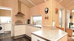 A modern kitchen with wooden walls, a built-in oven, a coffee maker, and a sink. - Modern Cottage With Spa - By Traum Ferienwohnungen (Sjølund)