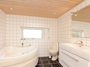 A bathroom with a bathtub, toilet, vanity, and a window.