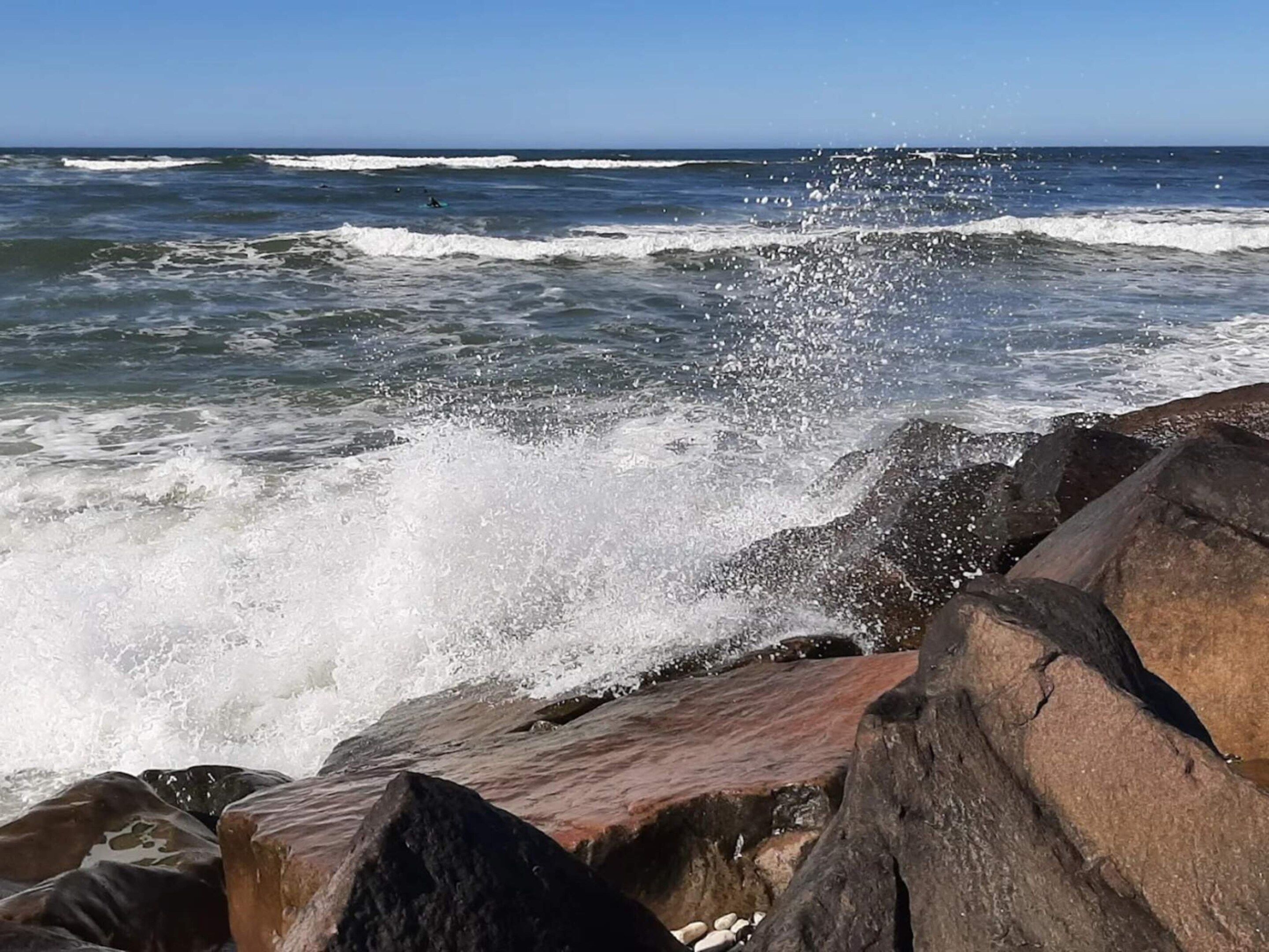 En stenet kystlinje med brusende bølger.