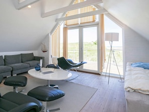 A modern room with a sofa, a round table, a bed, and a balcony with a view.