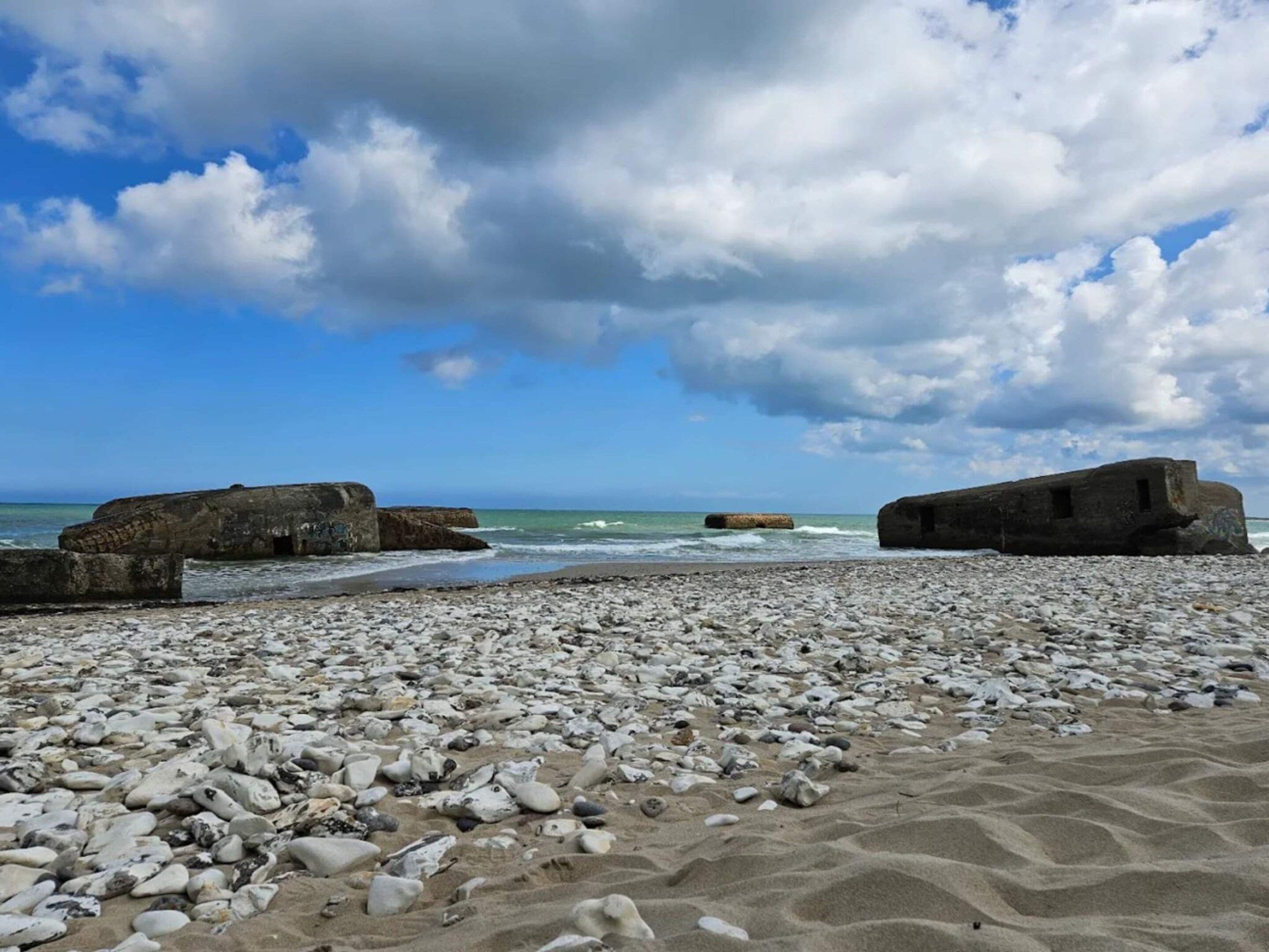 A rocky beach with large boulders and a clear sky.