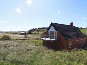 A single-story house with a large glass door and a balcony, surrounded by natural landscape. - 4 Star Holiday Home in Hanstholm (Hanstholm)