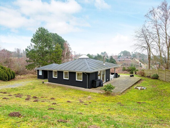 A black house with a sloped roof, a chimney, and a deck.
