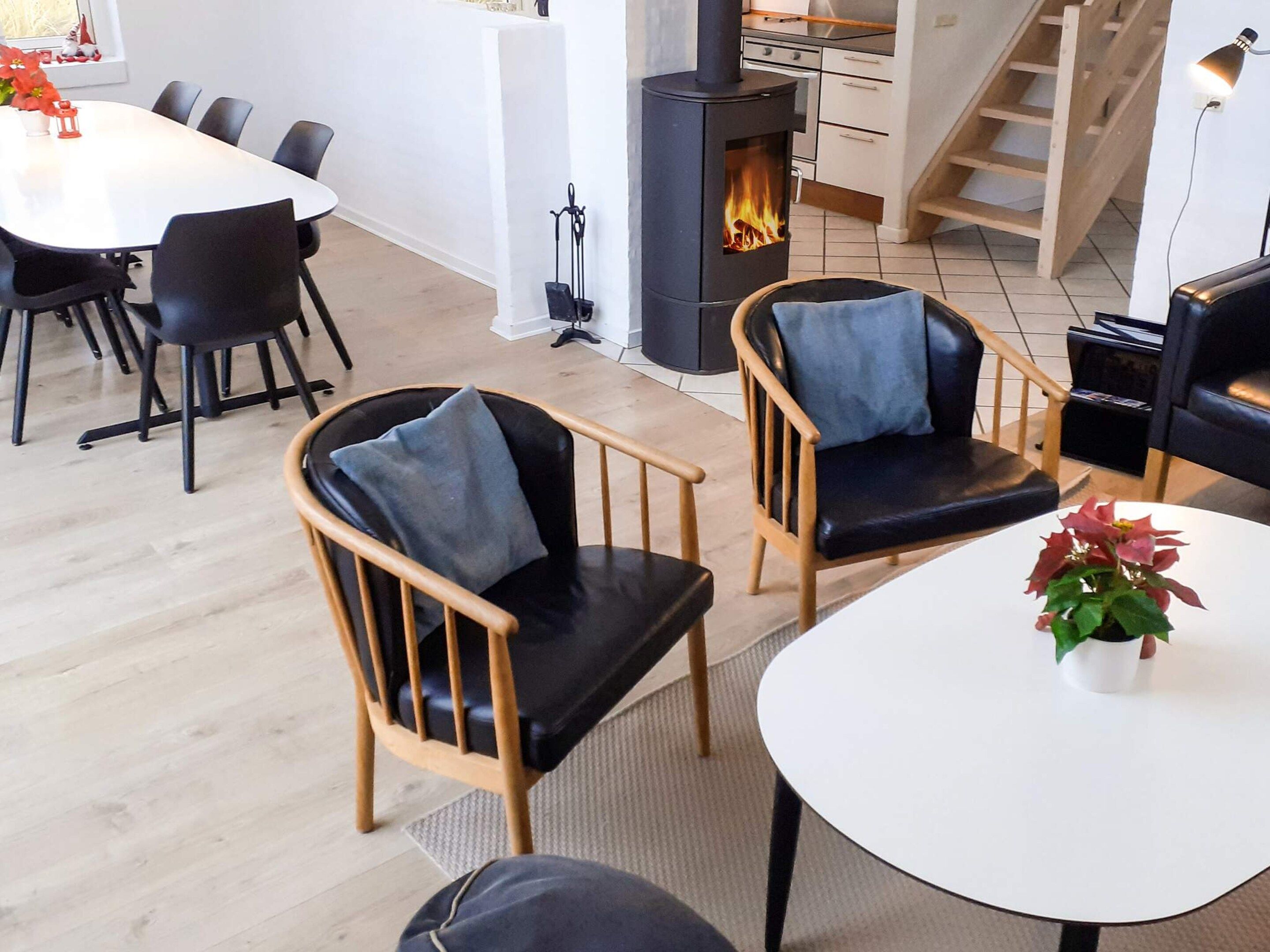 Ein modernes Wohnzimmer mit Kamin, Holzstühlen, einem Esstisch und einer Treppe.