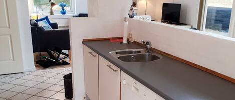 A compact kitchen with a sink, cabinets, and a window.