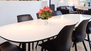Un comedor moderno con una mesa blanca, sillas negras y una planta en maceta con flores rojas.