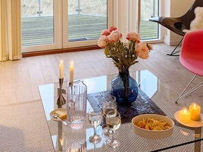 Een eettafel met kaarsen, een bloemetjesvaas en een schaal chips.