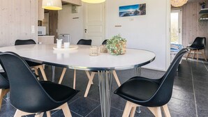 A modern dining area with a round table, black chairs, and pendant lights.