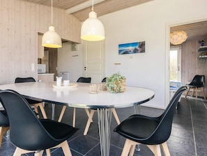 A modern dining area with a round table, black chairs, and pendant lights. - 4 Star Holiday Home in Lokken (Lokken)