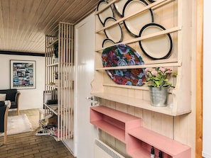 A room with a wooden wall, a colorful abstract painting, a metal bucket with flowers, and a framed photo on the wall. - 4 Star Holiday Home in Lokken (Lokken)