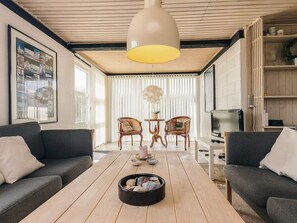 A modern living room with a wooden ceiling, two sofas, a coffee table, and a television.