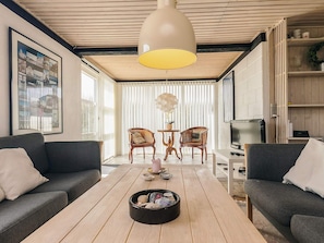Ein modernes Wohnzimmer mit zwei Sofas, einem Couchtisch, einem Fernseher und einer großen Pendelleuchte.