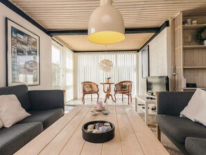 A modern living room with two sofas, a coffee table, a TV, and a large pendant light.