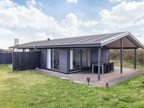 A modern house with a covered patio, large sliding glass doors, and a fenced yard.