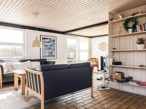 En hyggelig stue med sofa, sofabord i træ, reol og fjernsyn.
