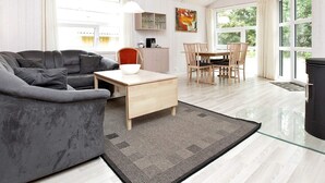 A modern living room with a grey sofa, a wooden coffee table, and a dining area with a table and chairs.