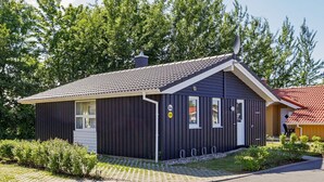 A small, dark-colored building with a tiled roof, a door, and a window.