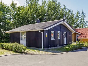 A small, dark-colored building with a tiled roof, a door, and a window. - Holiday Home in GrÃ¶mmitz (Groemitz)