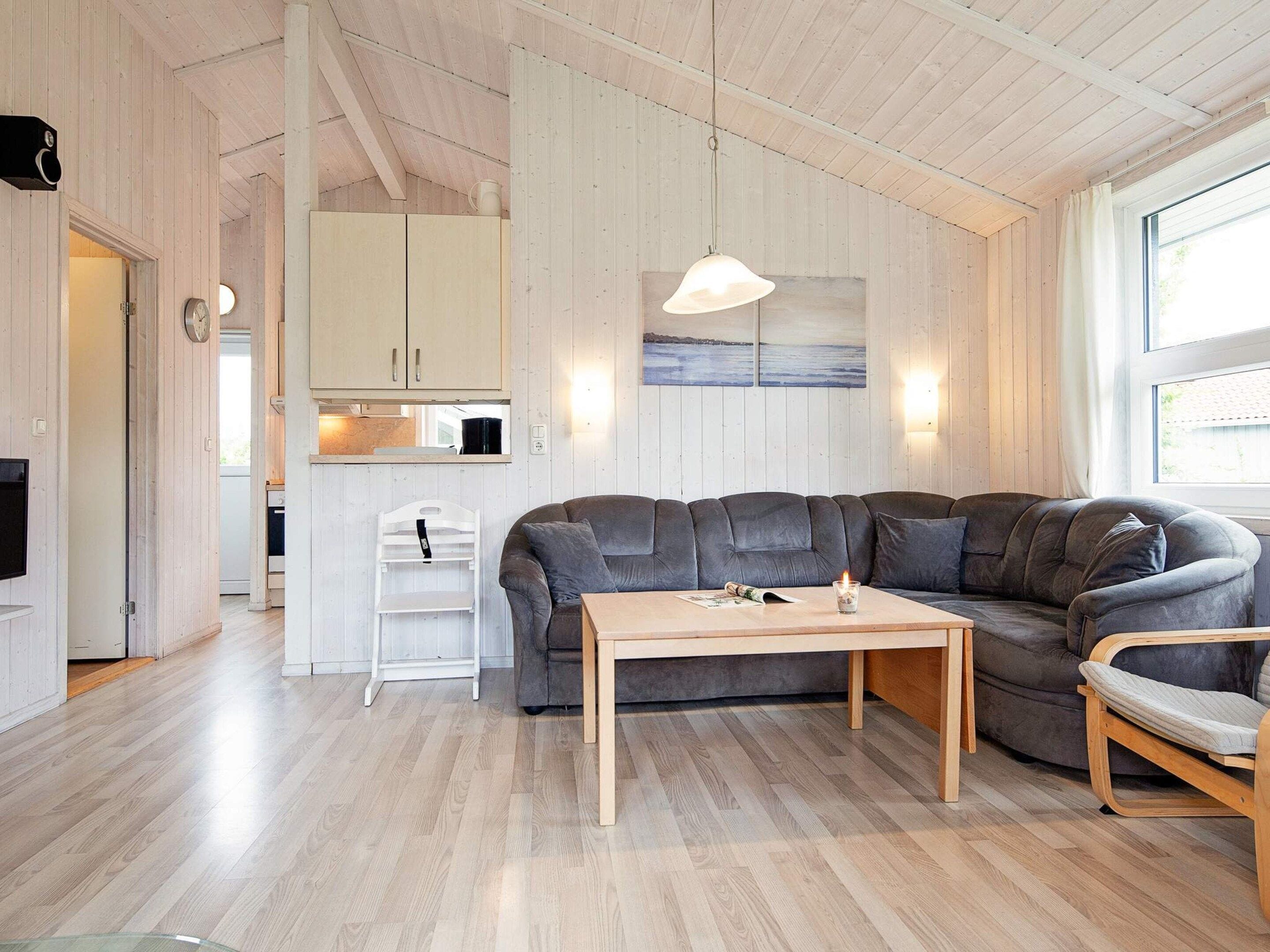 A modern living room with a sectional sofa, a wooden coffee table, and a dining area with a white chair.
