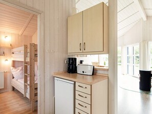 A compact room with a bunk bed, a small kitchenette with a coffee maker, and a window providing natural light. - Holiday Home in GrÃ¶mmitz (Groemitz)