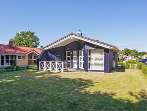 A single-story house with a sloped roof, a fenced patio area, and a clear sky.