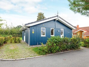 A single-story blue house with a gabled roof, a small porch, and a paved driveway.