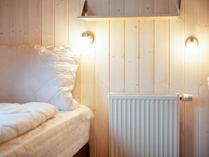 A bedroom with a bed, a white radiator, and two wall-mounted light fixtures. - Holiday Home in GrÃ¶mmitz (Groemitz)