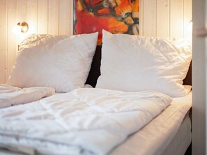 A bed with white bedding and a painting on the wall behind it. - Holiday Home in GrÃ¶mmitz (Groemitz)