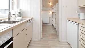 A narrow kitchen with a sink, coffee maker, and a radiator in the background.