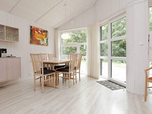 A dining area with a wooden table and chairs, a cabinet with glassware, and a painting on the wall. - Holiday Home in GrÃ¶mmitz (Groemitz)