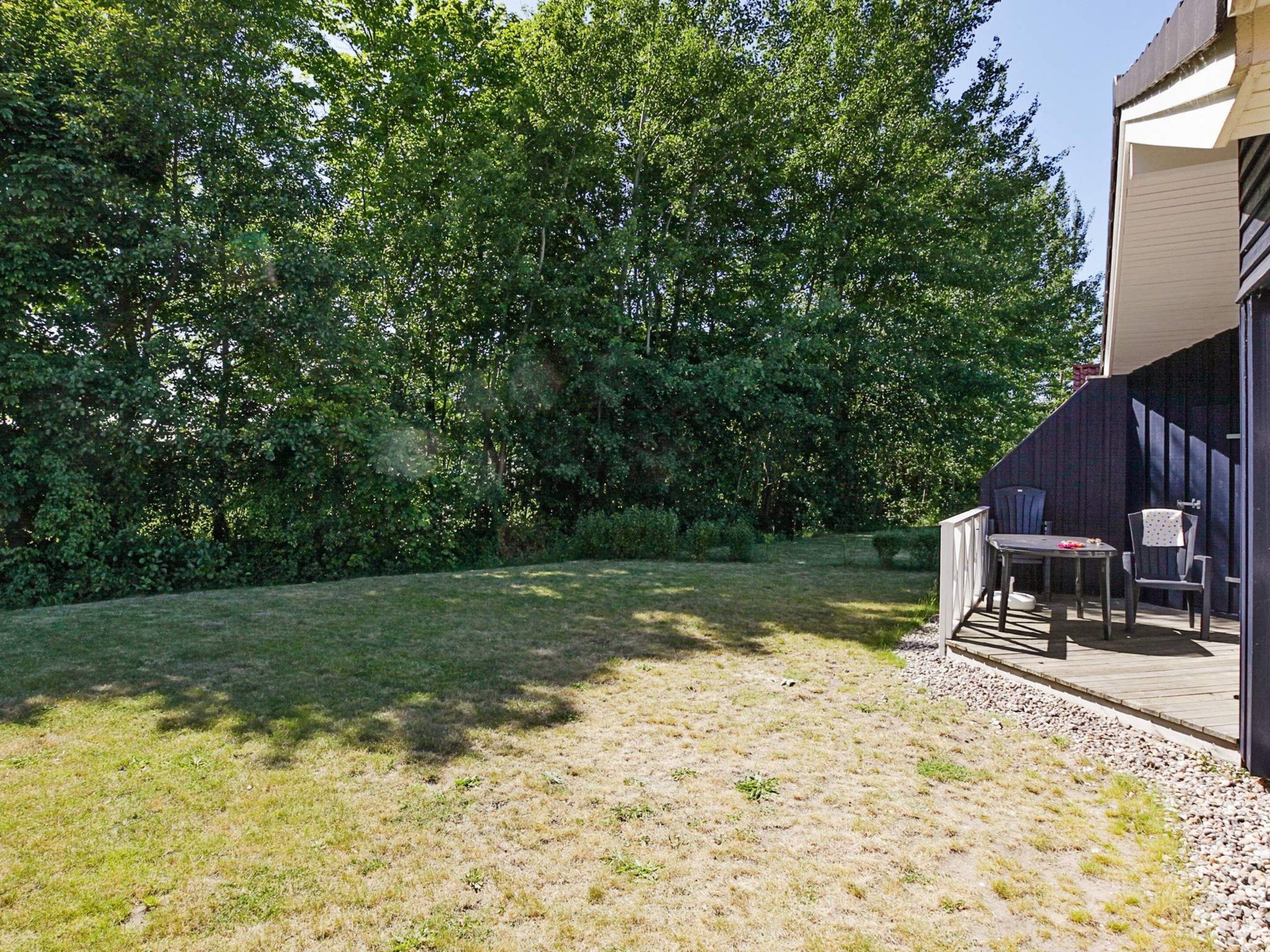 A backyard with a patio area, a table, and two chairs.