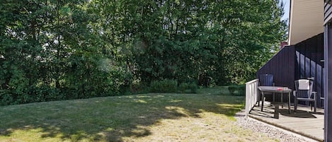 A backyard with a patio area, a table, and two chairs.