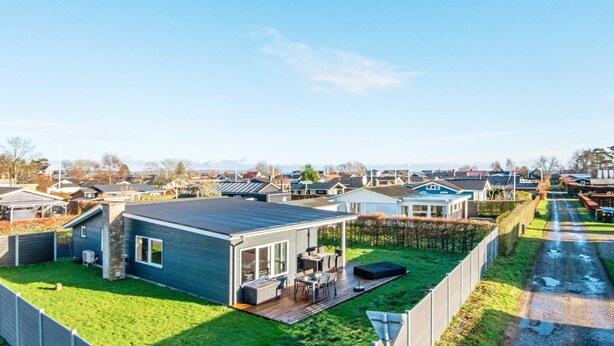 A modern mobile home with a deck and outdoor seating area, surrounded by a well-maintained lawn and a paved driveway. - 4 Person Holiday Home in Borkop-by Traum (Borkop)