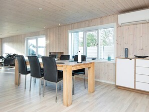 A modern kitchen with wooden walls, a dining area with a wooden table and chairs, and large windows providing natural light. - 4 Person Holiday Home in Borkop-by Traum (Borkop)