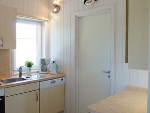 A kitchen with a sink, a coffee maker, a dishwasher, and a window.
