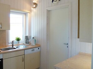 A kitchen with a dishwasher, a coffee maker, and a small potted plant on the counter.