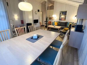A modern living room with a dining area, a sofa set, a TV, and a fireplace.
